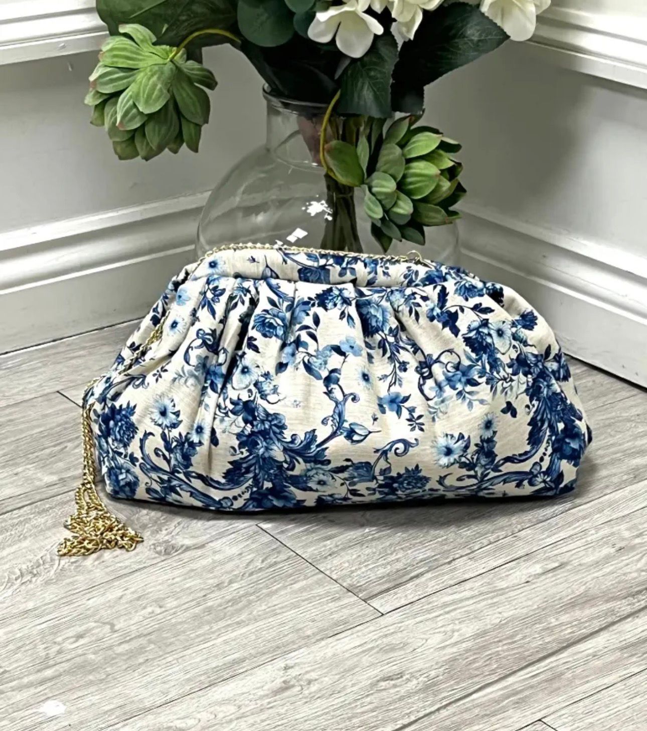 Blue floral clutch bag with detachable gold chain strap and gathered design.