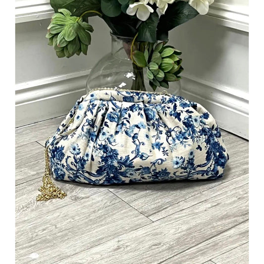 Blue floral clutch bag with detachable gold chain strap and gathered design.