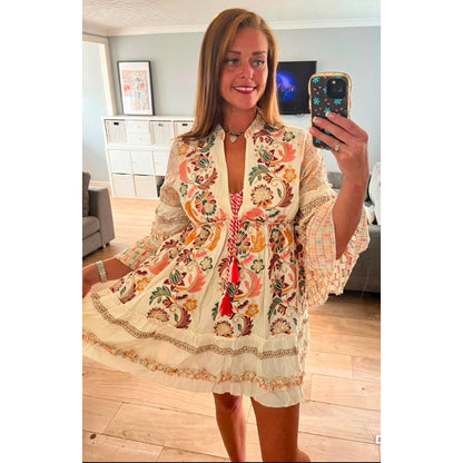 Model wearing the embellished boho tassel dress with embroidered detailing, tassel waist tie and frill hem in white. Available in white and black